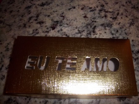 Caixa dourada decorada com a frase "EU TE AMO", com três pães de mel grande
